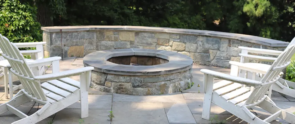 Circular fire pit in Chevy Chase, MD, with chairs and a seating wall.