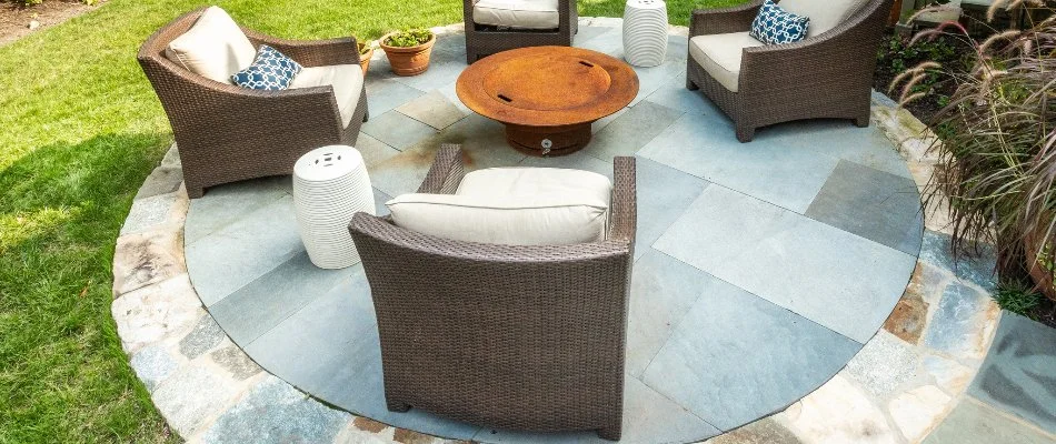 A circular patio made with stone and concrete in Chevy Chase, MD, with chairs and a table.  