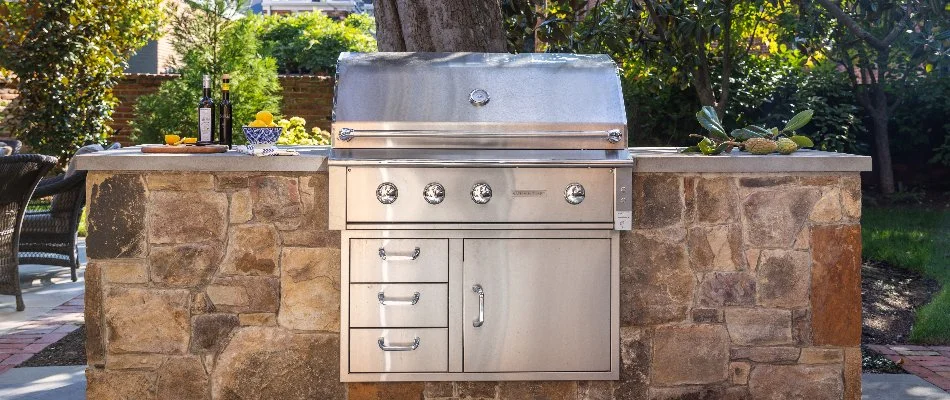Outdoor kitchen in Chevy Chase, MD, made of stone with a grill.