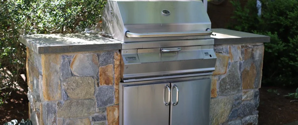 Stone outdoor kitchen in Chevy Chase, MD, with a stainless-steel grill.