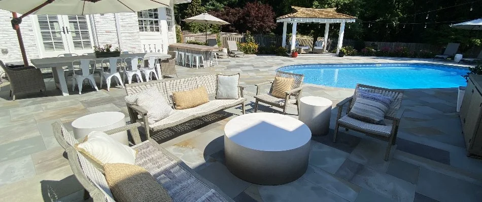 Patio in Bethesda, MD, with furniture and pergola near a swimming pool.