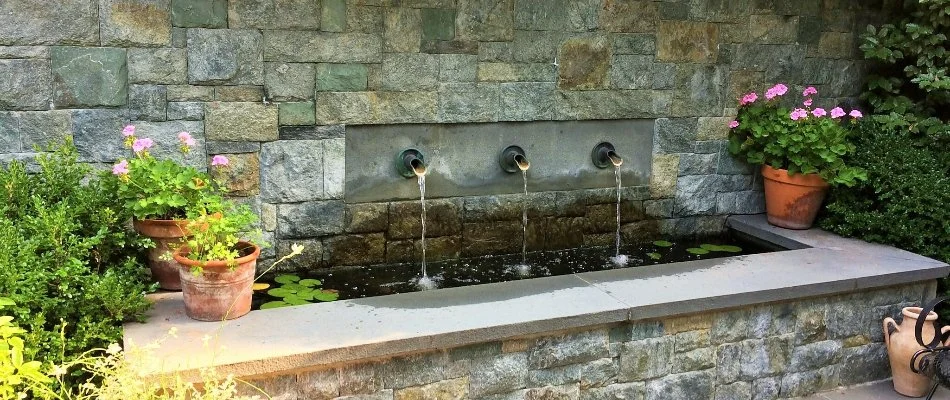 A water fountain in a stone wall on a property in Chevy Chase, MD.