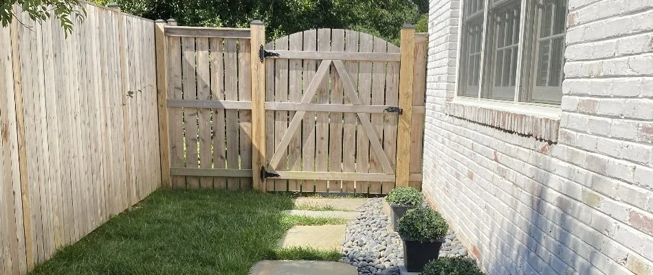 A wood fence in Chevy Chase, MD, with a stone walkway leading to the gate near the side of a house and a rock landscape bed.