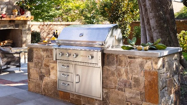 An outdoor kitchen made of stone with a grill in Potomac, MD.