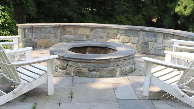 A stone fire pit in Bethesda, MD, with a wall and white seating.